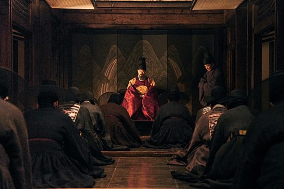 Cena do filme The Fortress mostrando o Rei Injo sentado ao centro cercado por seus ministros ajoelhados em um debate político tenso dentro da fortaleza